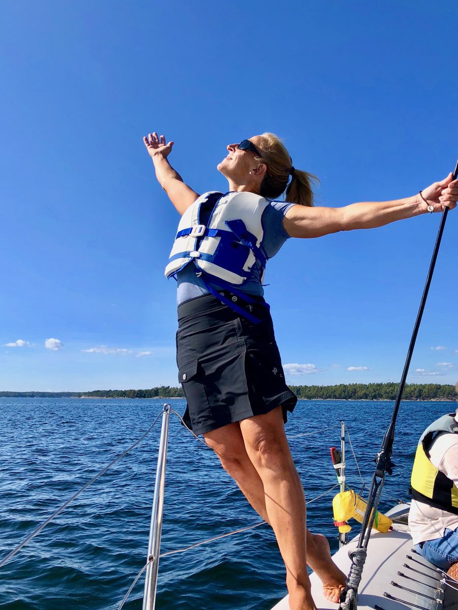 Pia L'Obry med utsträckta armar i fören på en segelbåt